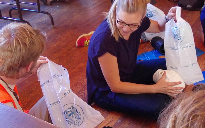 Two people hold some sort of plastic bags as they participate in a WFA certification course. 